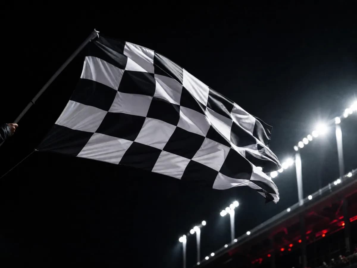A chequered flag waving under floodlights